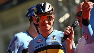 Remco Evenepoel, wearing a helmet, smiles before a cycling race.
