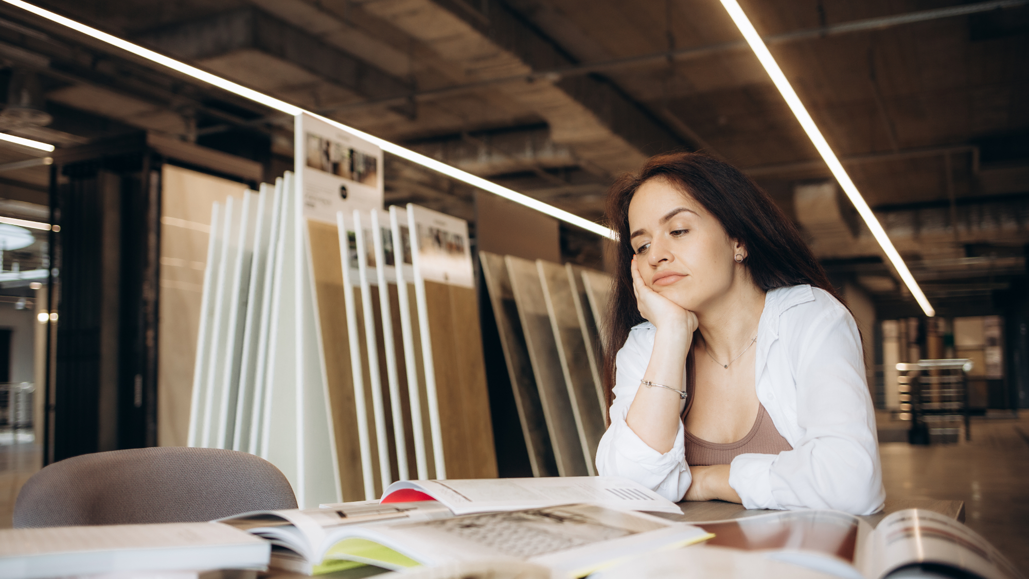 woman sat at table in flooring shop looking at samples
