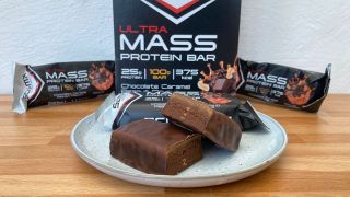 Ultra Mass Protein Bar cut in half on plate, shown with packaging