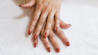 Hands with dark orange nail polish