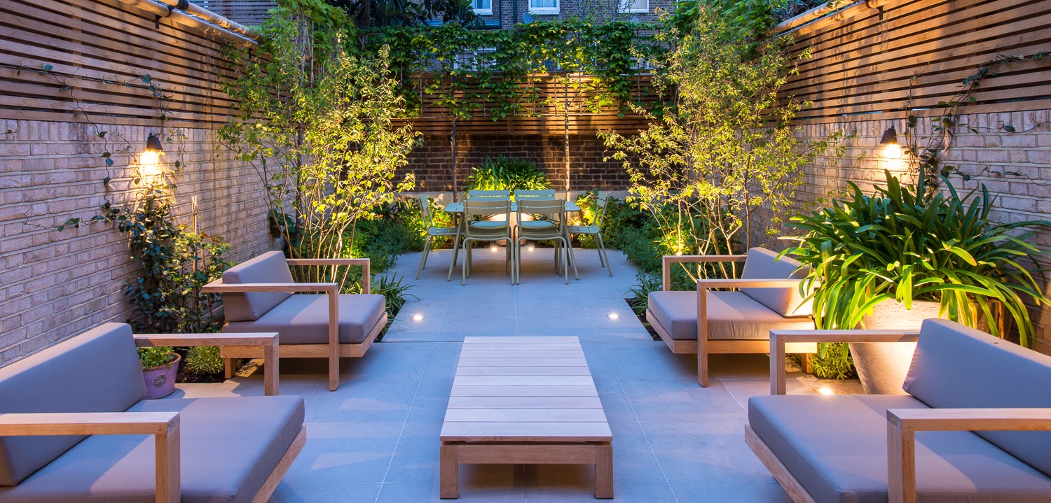large courtyard garden with furniture lit by lighting