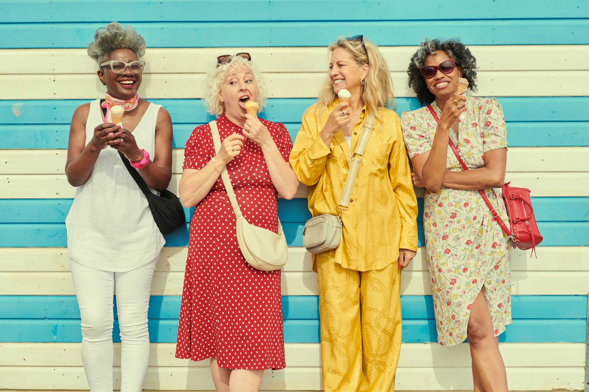 Four mature women eating ice cream cones.