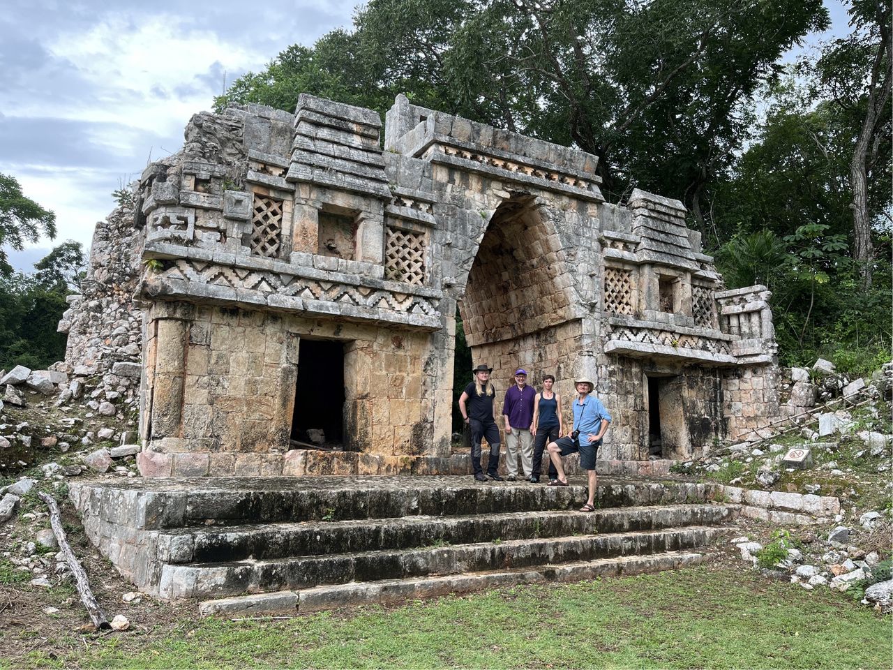 A group of people stand in front of an intricate Maya temple