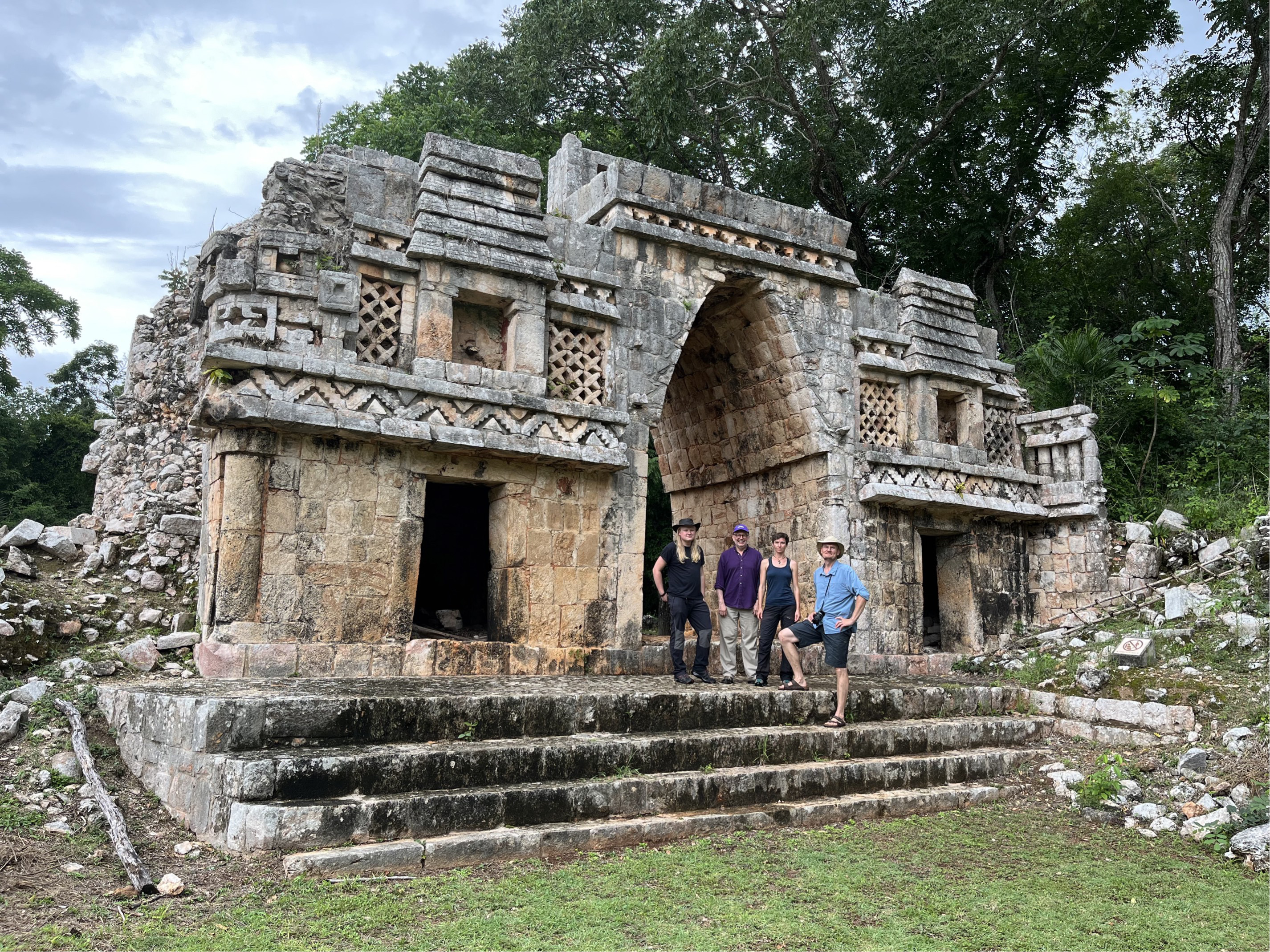 A group of people stand in front of an intricate Maya temple