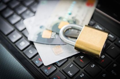 Padlock and stack of credit cards on top of laptop