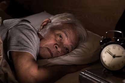A man lays in bed while having trouble sleeping. 