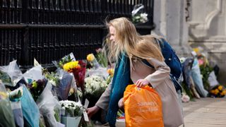 a woman adds a bunch of flowers to a line of floral tributes against the railings at the front of buckingham palace in central london on april 9, 2021 after the announcement of the death of britains prince philip, duke of edinburgh queen elizabeth iis husband prince philip, who recently spent more than a month in hospital and underwent a heart procedure, died on april 9, 2021, buckingham palace announced he was 99 photo by tolga akmen afp photo by tolga akmenafp via getty images