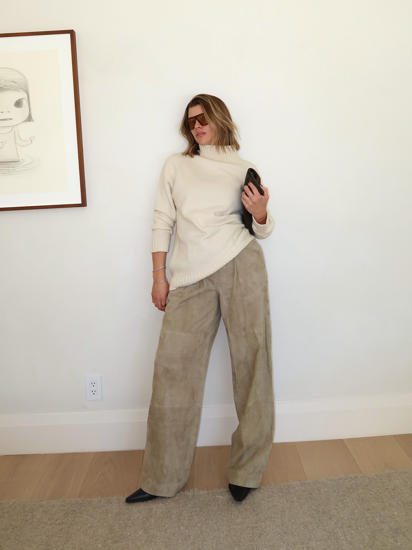 Sofia Grainge in beige suede pants and white sweater turtleneck.