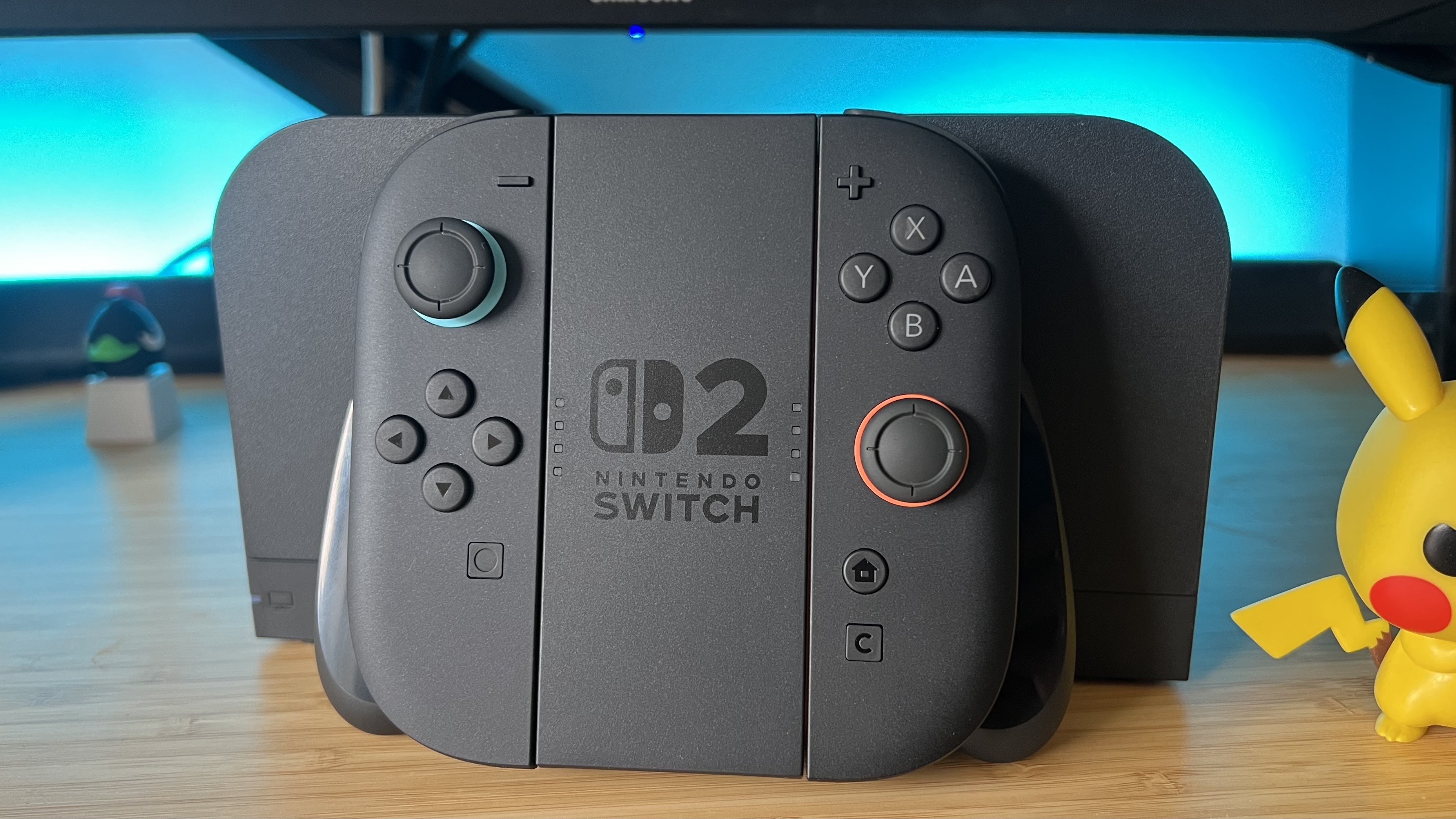 Nintendo Switch 2 Joy-Con in Joy-Con grip on a wooden desk with blue backlighting