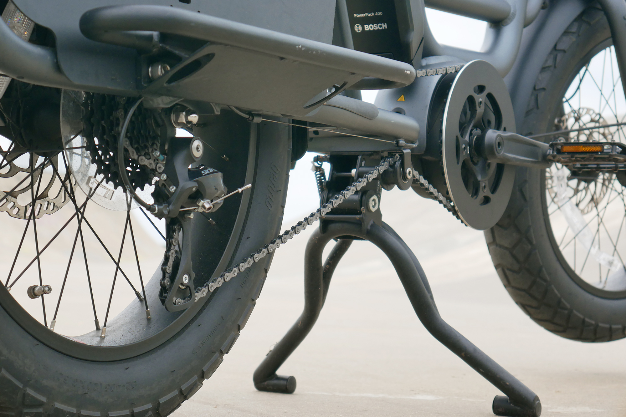 Very wide and low hanging kickstand of the Benno RemiDemi XL against the backdrop of a concrete skatepark