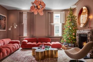 a pink living room with a christmas tree put up