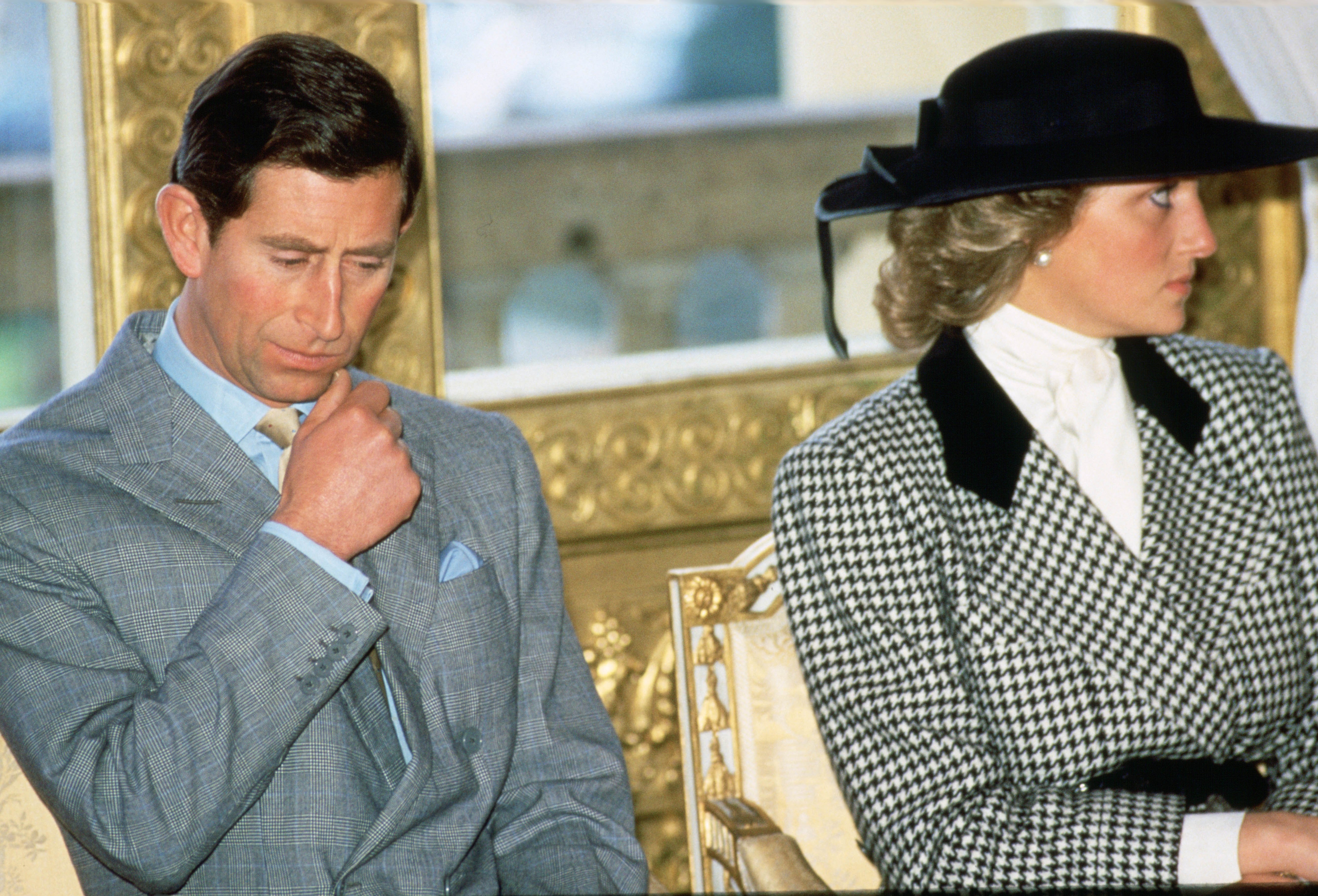 Princess Diana wearing a white and black blazer and Prince Charles in a gray suit