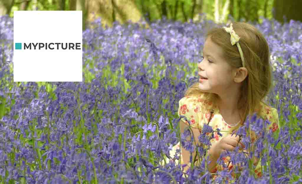My picture logo placed over a young girl posing in a field of bluebells