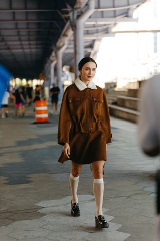 woman wearing jacket, skirt, loafers, and socks.