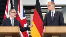 Keir starmer, left, and friedrich merz, right, look at eachother from behind podiums in front of union jack and german flags