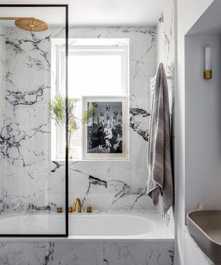 White marble bathroom with brass taps and brass shower head