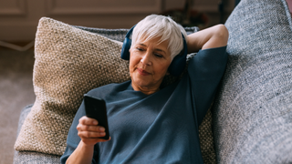 Woman listening to phone while lying on sofa