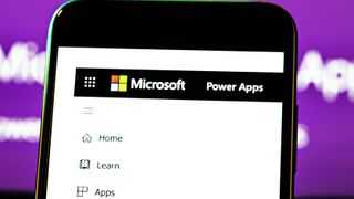 A smartphone with Microsoft's Power Apps homepage displayed on a purple background