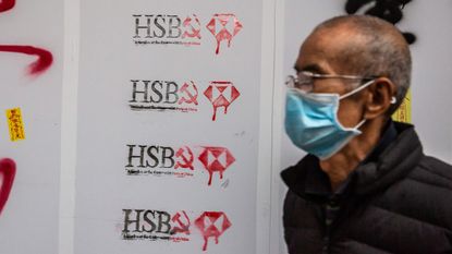 Man walks in front of vandalised HSBC store in Hong Kong