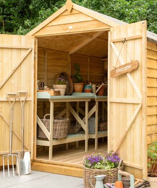 Wooden shed with doors open to reaveal storage space inside with garden tools and shelving