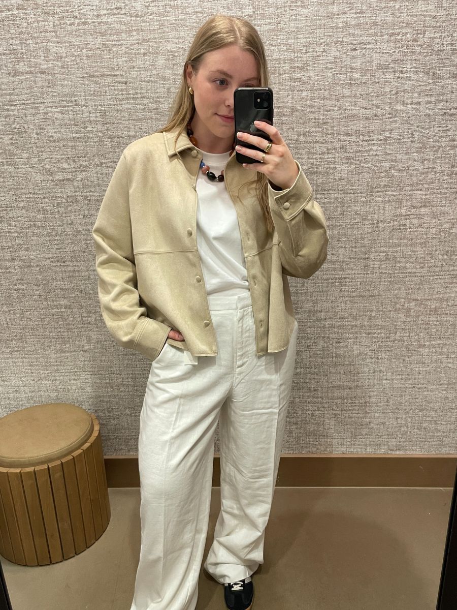 Woman in mirror wears yellow suede jacket, white T-shirt and white linen trousers