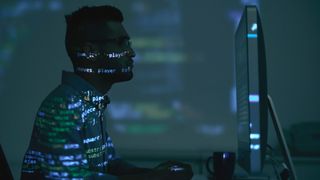 man coding on computer with code lighting up his face