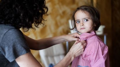 Woman buttoning the shirt of a young girl
