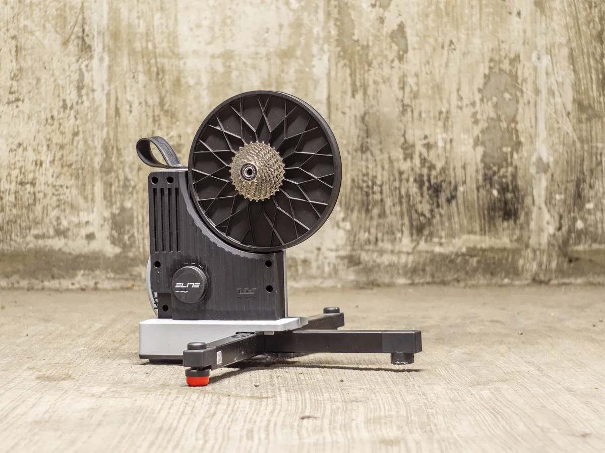 Side angle of the Elite Justo 2 Smart Trainer outdoors in front of a wall