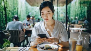 Woman eating at a restaurant looking at her phone