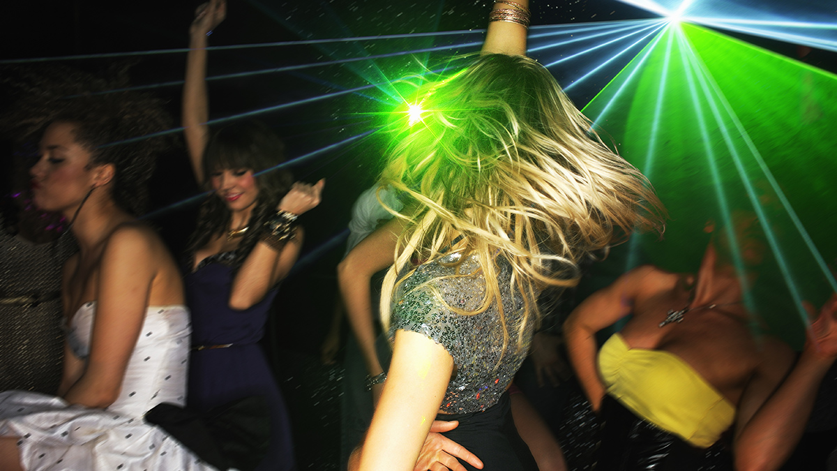 Group of young people dancing in nightclub with laser lighting.