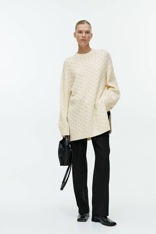 arket sale - woman wearing long cream cable knit jumper 