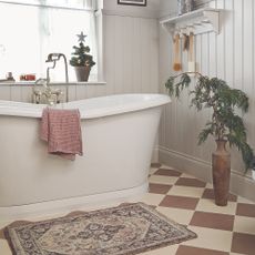 Bathroom with cream and terracotta floor tiles and white freestanding bath