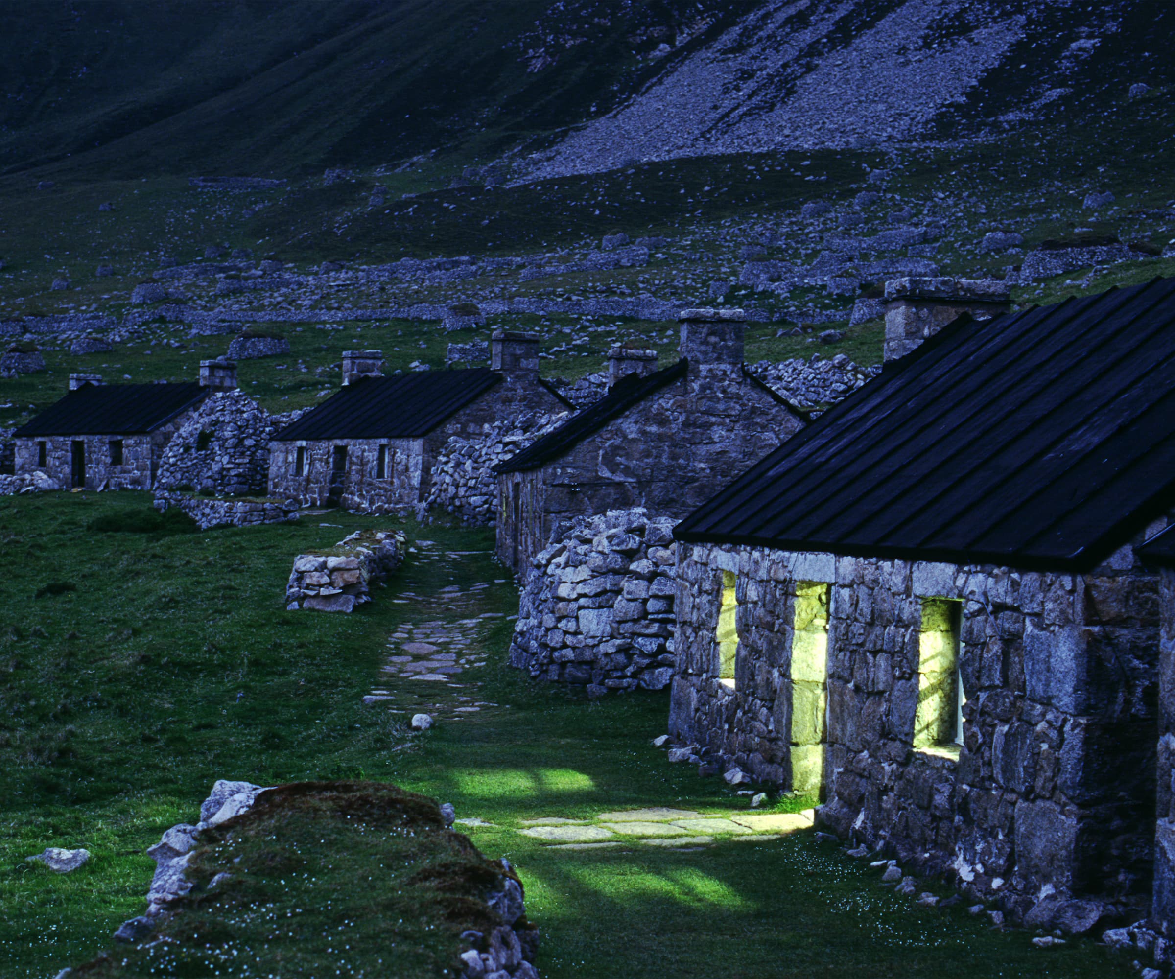 A stone house in the Outer Hebrides with its lights on