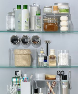 Glass bathroom shelves with toiletries displayed along them