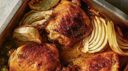 A baking tray with baked fennel and chicken thighs