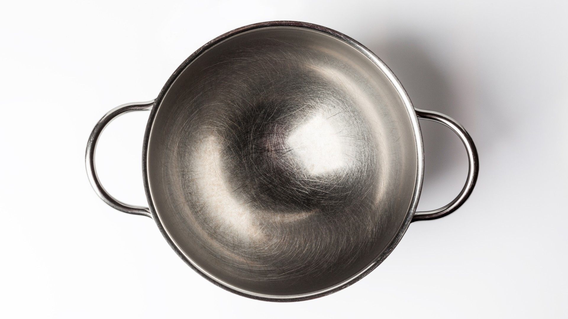 an empty stainless steel mixing bowl on a white surface