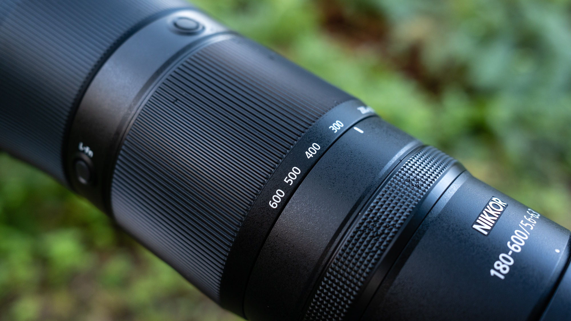 Close up photos of the Nikkor Z 180-600mm f/5.6-6.3 VR mounted on a tripod with foliage in the background