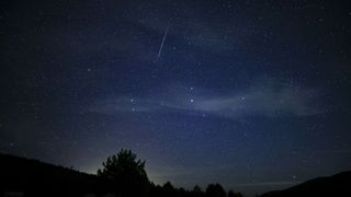 a bright streak of light crosses a starry night sky