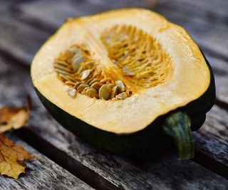 An acorn squash sliced in two revealing the flesh and seeds