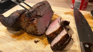 Roast beef cooked using an air fryer being sliced on a chopping board