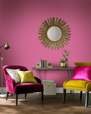 Lille pink paint color on living room wall with pink velvet and mustard yellow armchairs with gold feather-style sunburst mirror