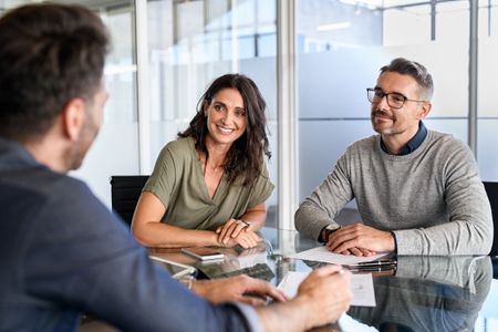 Smiling mature couple meeting with an adviser for estate planning.