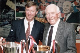 Manchester United managers past and present Sir Alex Ferguson poses alongside Sir Matt Busby and their respective European trophies in October 1991.