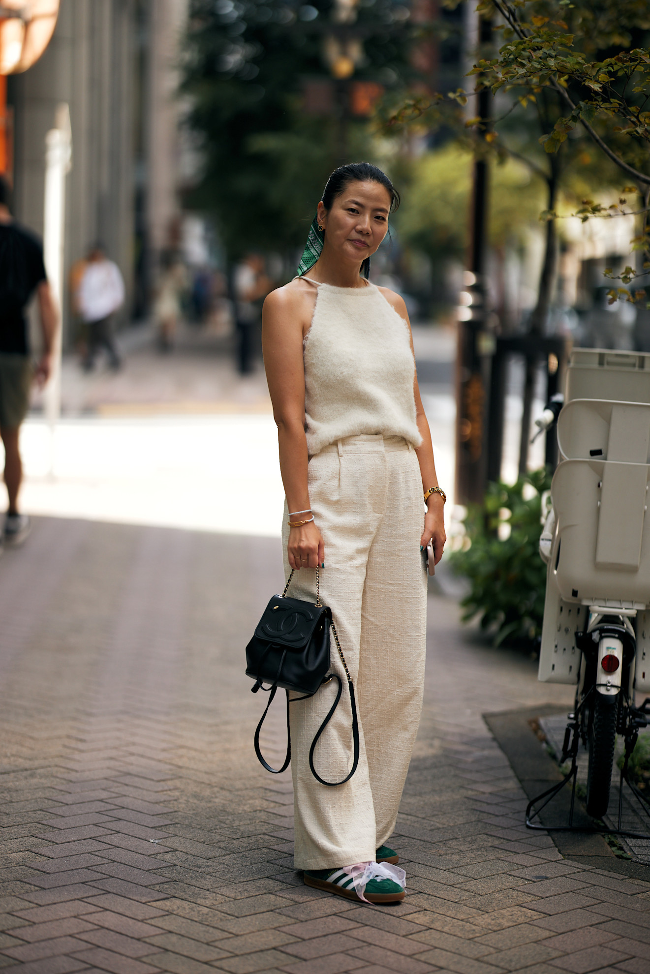fashion week attendee wearing cream tank top, pants, green sneakers