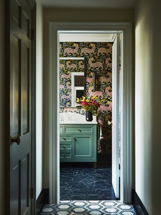 A bathroom with green vanity, and wallpaper on the walls