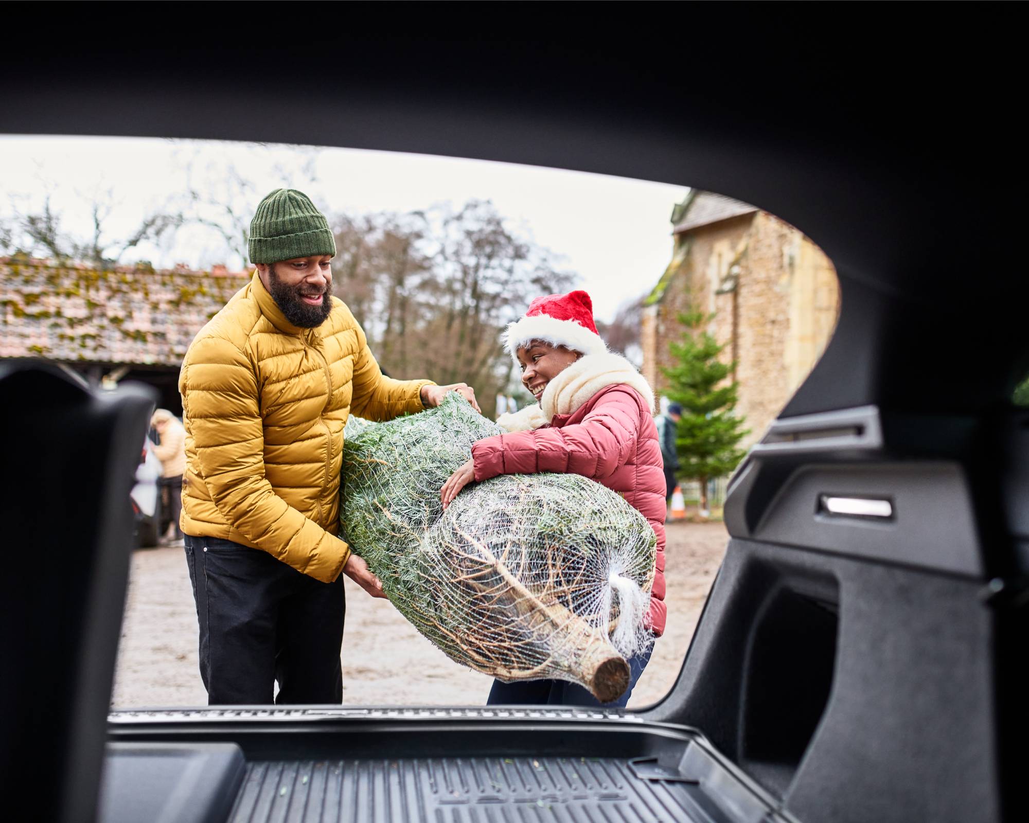 Couple loading live Christmas tree into car