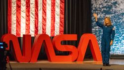 people in blue jumpsuits smile and wave.