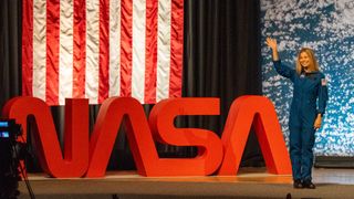 people in blue jumpsuits smile and wave.