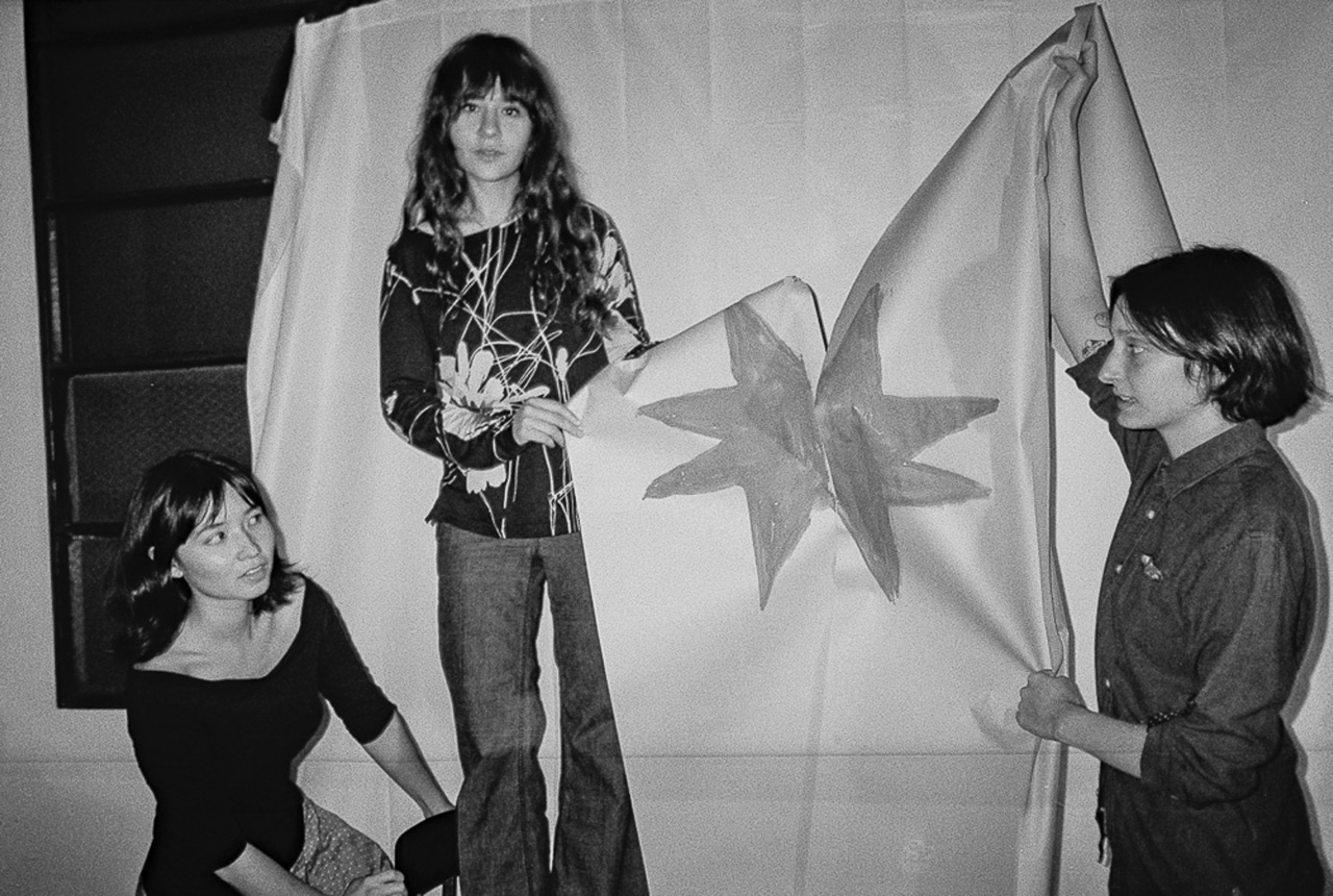 The Horsegirl trio in black and white, holding a flag