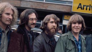 Creedence Clearwater Revival standing in front of an airport arrivals sign